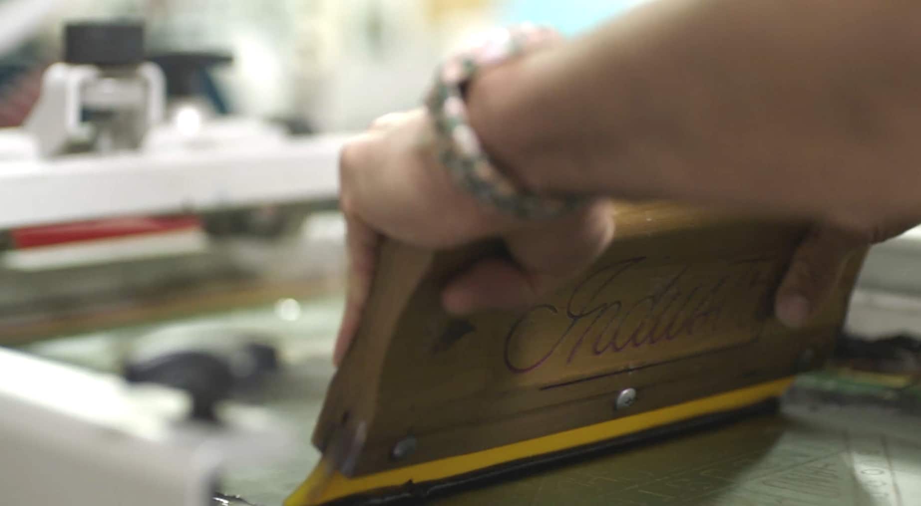 Screen printer pulling a squeegee across a screen